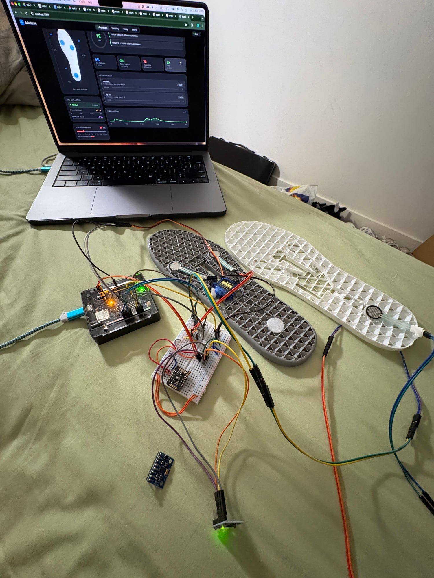 Force sensors wired into two 3D-printed lattice insoles, connected through a breadboard to the Arduino, with the live dashboard on a laptop behind.